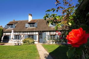 una casa con una rosa roja delante de ella en Le Verdoyant, en Verneuil d'Avre et d'Iton