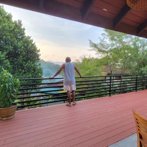 a man standing on a deck looking out at the mountains at Pinnacle of Everything in Kandy