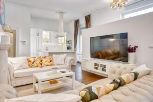 a living room with white furniture and a large flat screen tv at Apartments Old Town Gloria in Zagreb