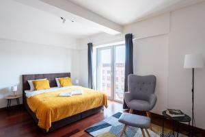 ein Schlafzimmer mit einem Bett, einem Stuhl und einem Fenster in der Unterkunft Apartments with large balcony, parking Prague in Prag