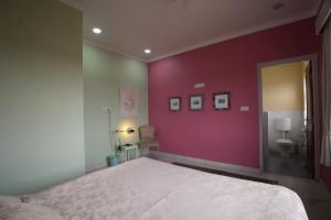 - une chambre avec un grand lit et un mur rose dans l'établissement lalita homestay countryside, à Khajurâho