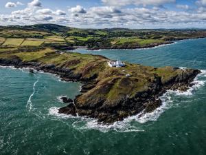 an island in the ocean with a house on it at East Point Lynas Lighthouse Keeper's Cottage in Amlwch