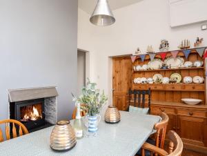 a dining room with a table and a fireplace at East Point Lynas Lighthouse Keeper's Cottage in Amlwch