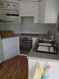 a kitchen with a stainless steel sink and white cabinets at Garten-Wohnung in Eschen