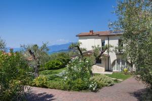 ein weißes Haus mit Bäumen und einer steinernen Einfahrt in der Unterkunft Villa Lisi With Pool in Bardolino