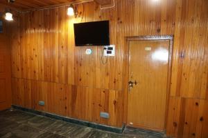 a room with a wooden wall with a door and a television at Aubiz Villa in Srinagar