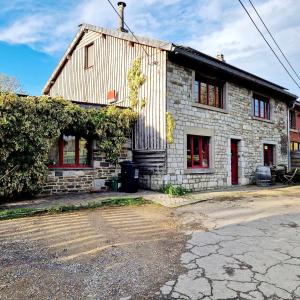 una antigua casa de piedra con ventanas rojas y aphalt en Le murmure des Lucioles, en Hamoir