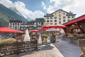 a group of buildings with tables and red umbrellas at La Croix Blanche in Chamonix-Mont-Blanc