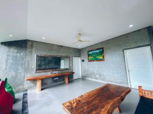 a living room with a wooden table and a tv at The Green Home Bali in Denpasar