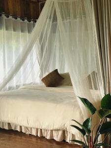een bed met witte klamboe in een slaapkamer bij Wanna’s house in Ban Huai Khai