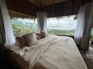 a bed in a room with a large window at Wanna’s house in Ban Huai Khai