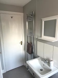Baño blanco con lavabo y espejo en Claygate Place - Modern 2 Bed House with Parking en Nottingham