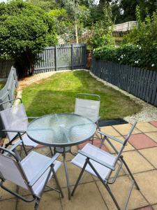 een glazen tafel en 4 stoelen op een patio bij Claygate Place - Modern 2 Bed House with Parking in Nottingham