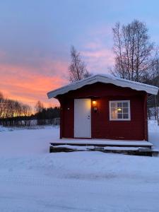 ein kleines Haus im Schnee mit Sonnenuntergang im Hintergrund in der Unterkunft Hyttgårdens stugby i Huså, Åre kommun in Huså