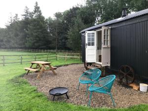 a picnic table and chairs next to a black shed at Hexhamshire Shepherd Hut in Hexham
