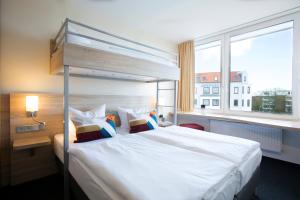 a bedroom with a large white bed and a window at Atlantic Hotel am Floetenkiel in Bremerhaven