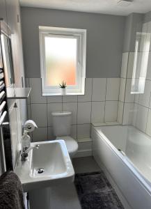 a bathroom with a tub and a toilet and a window at Claygate Place - Modern 2 Bed House with Parking in Nottingham