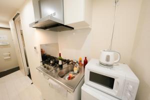 una pequeña cocina con fregadero y microondas en FL Residence Shinjuku II, en Tokio