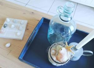 a blue tray with a bottle and a shell on a table at Beachfront at 22 Settler's Sands in Port Alfred