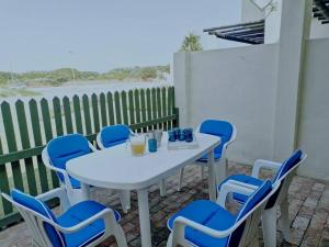 a white table and blue chairs on a patio at Beachfront at 22 Settler's Sands in Port Alfred