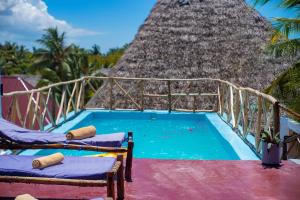 a resort pool with two chairs and a thatch roof at Babalao Rooftop Hotel in Paje