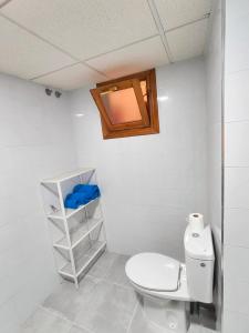 La salle de bains est pourvue de toilettes blanches et d'une étagère. dans l'établissement Mi refugio, à San Fernando