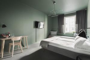 a bedroom with a bed and a desk and a window at Heimen Hotel in Bergen