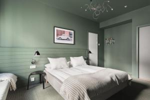 a bedroom with a bed with green walls and a chandelier at Heimen Hotel in Bergen