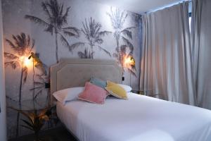 a bedroom with a white bed with colorful pillows at NATURA ROOMS 