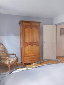 a bedroom with a wooden cabinet and a chair at Gîte les deux sources au pied du Vercors in Saint-Laurent-en-Royans
