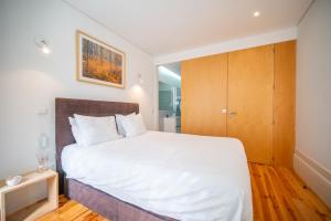 - une chambre avec un lit blanc et une armoire en bois dans l'établissement JOIVY Modern flat with patio in central Porto, à Porto