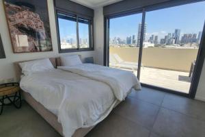 Schlafzimmer mit einem Bett mit weißer Bettwäsche und einem großen Fenster in der Unterkunft Penthouse Sea View in Ben Yehuda by HolyGuest in Tel Aviv