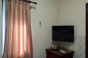 a room with a flat screen tv and a curtain at OYO 93060 Wisma Astukara Syariah in Enrekang