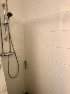 a shower with a hose in a white tiled bathroom at Top floor one bedroom apartment with balcony in Helsinki