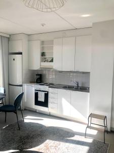 a kitchen with white cabinets and a refrigerator and a chair at Top floor one bedroom apartment with balcony in Helsinki