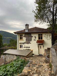 una pequeña casa blanca con un camino de piedra delante de ella en Spring House Изворна Къща, 