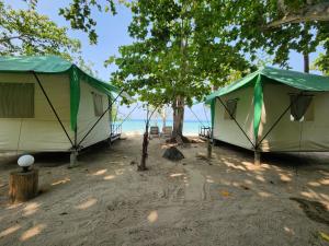 dwa namioty na plaży z drzewami i oceanem w obiekcie Koh Ngai Camping Restaurant @ Bar w Ko Ngai