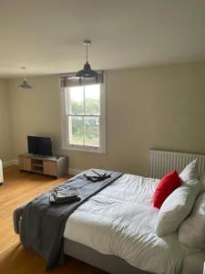 um quarto com uma cama com almofadas vermelhas e uma janela em Two Bedroom Duplex Apartment The Priory - St Ives em St Ives