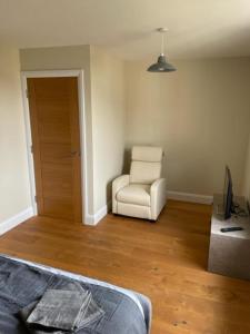 a bedroom with a chair and a bed and wooden floors at Two Bedroom Duplex Apartment The Priory - St Ives in St. Ives