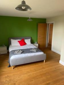 een groene slaapkamer met een bed met een rood kussen bij Two Bedroom Duplex Apartment The Priory - St Ives in St Ives