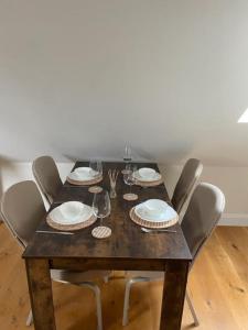 a wooden table with chairs and plates and wine glasses at Two Bedroom Duplex Apartment The Priory - St Ives in St. Ives
