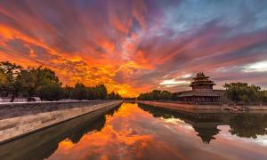 un coucher de soleil sur une rivière avec un bâtiment chinois dans l'établissement Happy Dragon City Culture Hotel -In the city center Close to Forbidden City&Wangfujing Street&Subway Nearby &free coffee & Free laundry&English speaking with tour services &Free WiFi unlimited for Western software, à Pékin