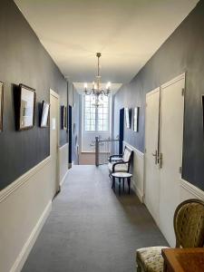 um corredor com paredes azuis e um lustre em Grand gîte pour 28 personnes dans un château en Normandie em Beuzevillette