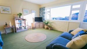 a living room with a blue couch and a large window at Pencoed in Llanbedrog