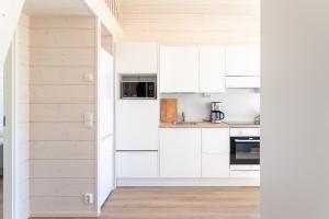 eine Küche mit weißen Schränken und einer offenen Tür in der Unterkunft Himoskuutio 4, erillistalo, ulkoporeallas in Jämsä