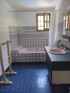 La salle de bains est pourvue d'une baignoire rose et d'un lavabo. dans l'établissement Gîte les deux sources au pied du Vercors, à Saint-Laurent-en-Royans