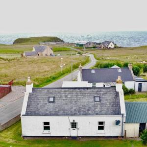 a white house with a gray roof next to the ocean at southview in Portskerra