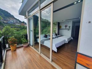 a bedroom with two beds and a balcony with windows at Phượng Chi Homestay Venuestay in Tam Ðảo