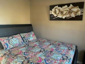 a bed with a colorful quilt and a picture on the wall at Little Farmhouse Near The Dairy in Warranulla