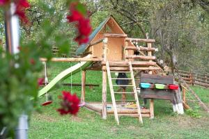 ein Baumhaus mit einer Rutsche im Gras in der Unterkunft La Răscoala in Petrila